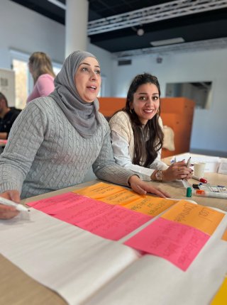 two women sitting at a table with workshop materials 